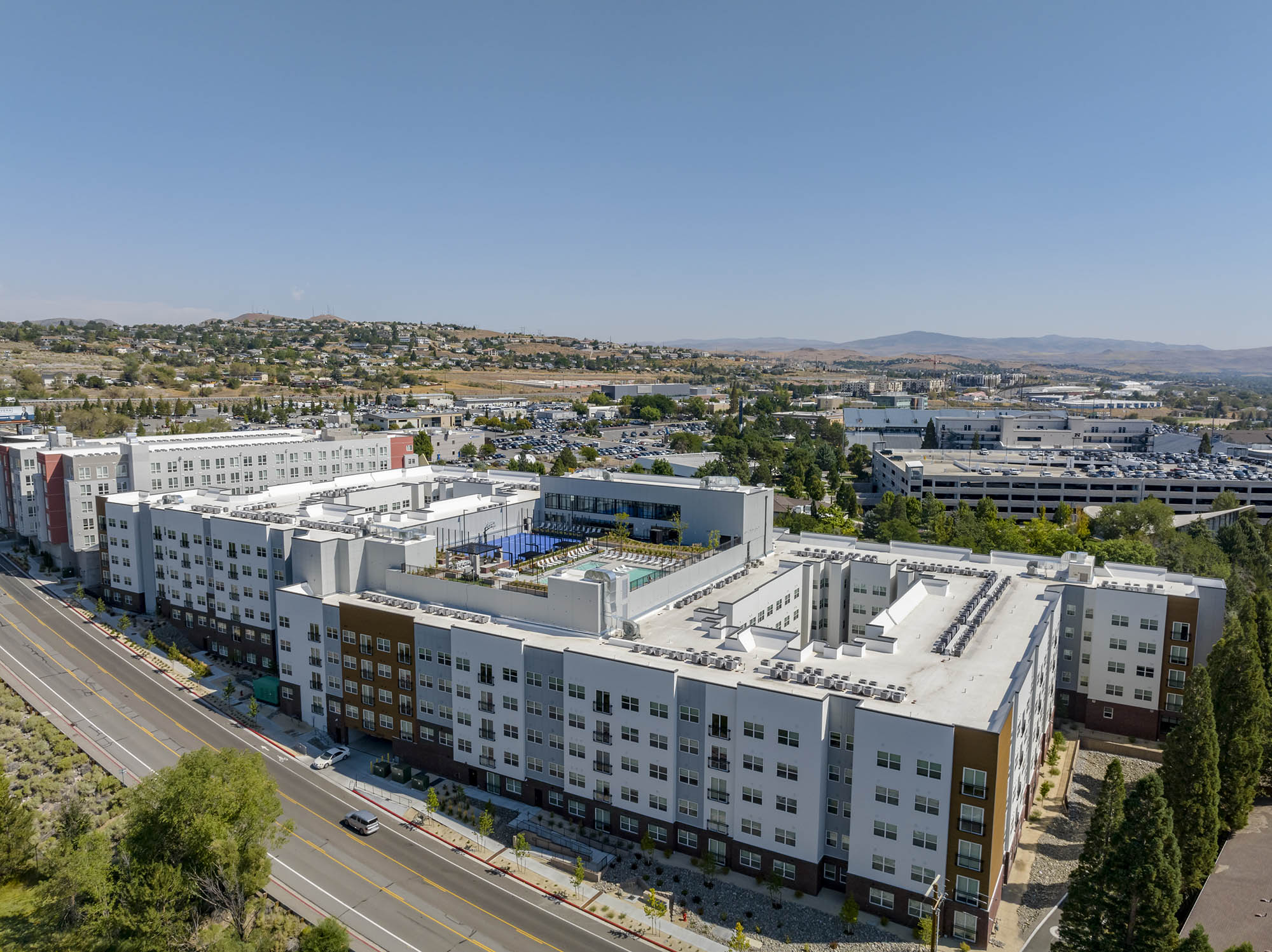 Aerial view of a modern apartment complex with nearby amenities