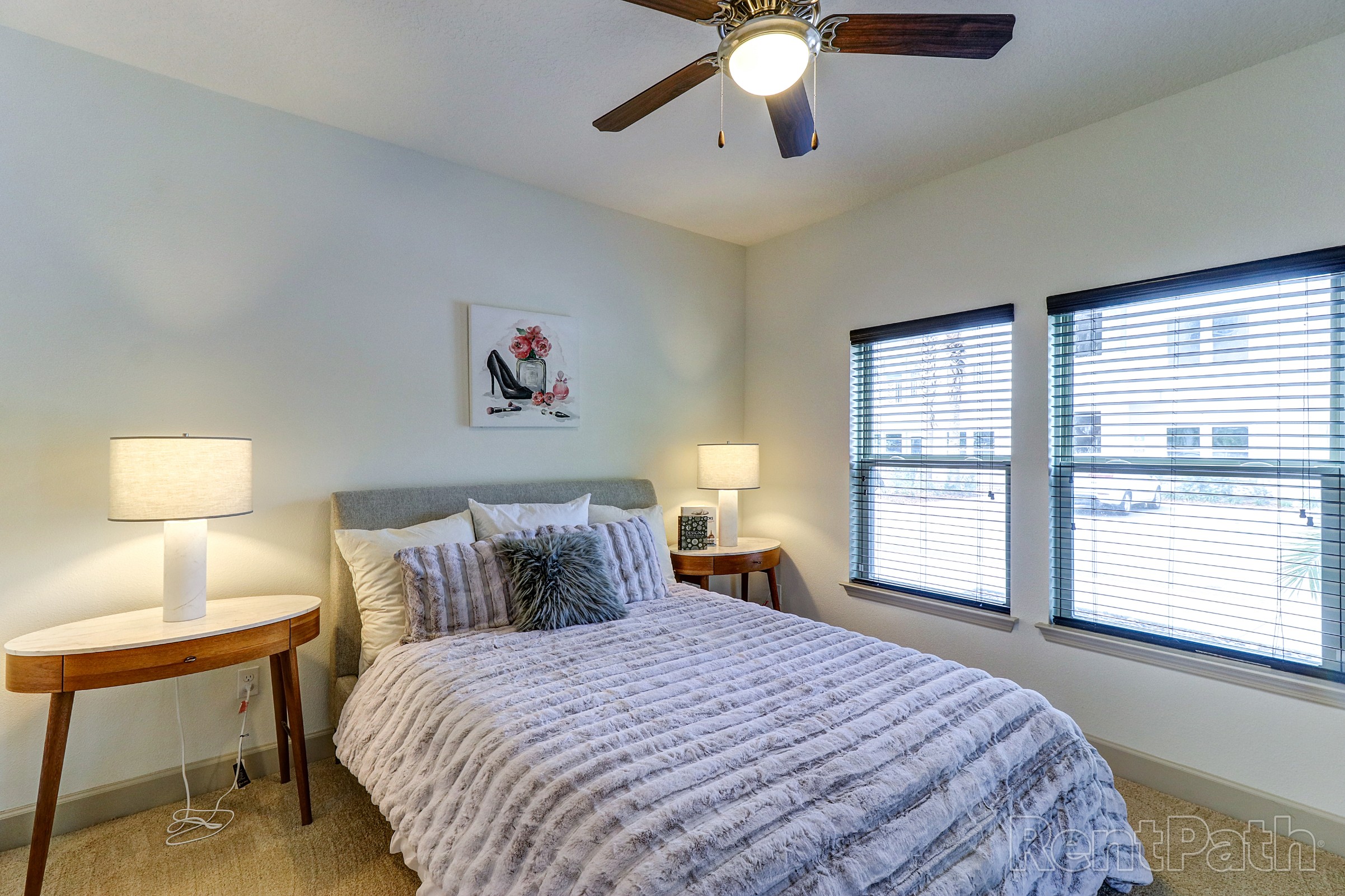 Model bedroom with ceiling fan and large windows at Astoria at Celebration
